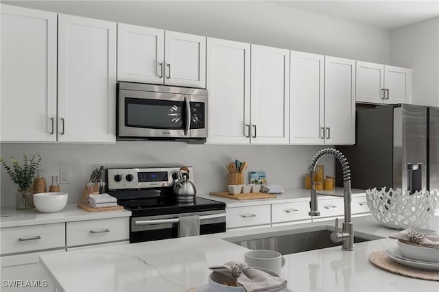 kitchen with stainless steel appliances, white cabinetry, and sink