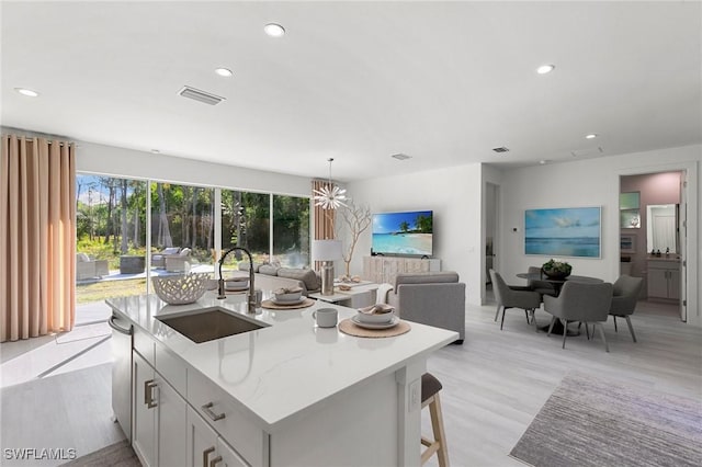 kitchen featuring light stone countertops, a kitchen island with sink, and sink