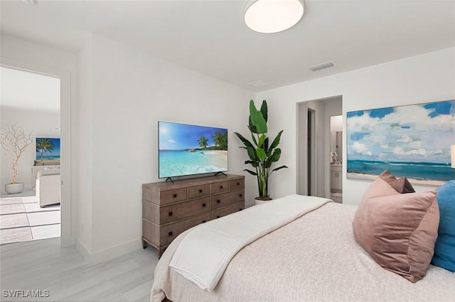 bedroom with light hardwood / wood-style floors and ensuite bathroom