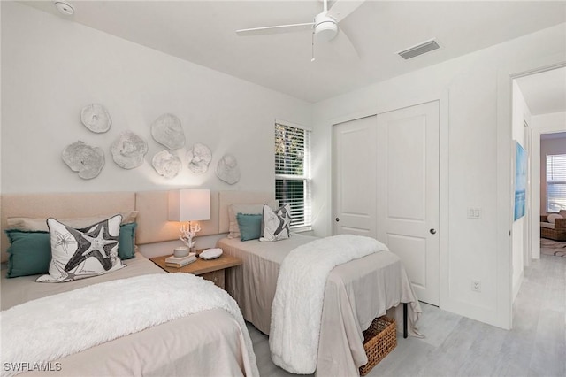 bedroom with multiple windows, ceiling fan, a closet, and light hardwood / wood-style flooring