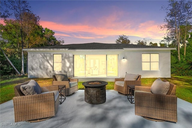 back house at dusk with a patio and an outdoor living space with a fire pit