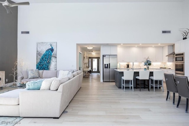 living room featuring a chandelier, a high ceiling, and light wood-type flooring