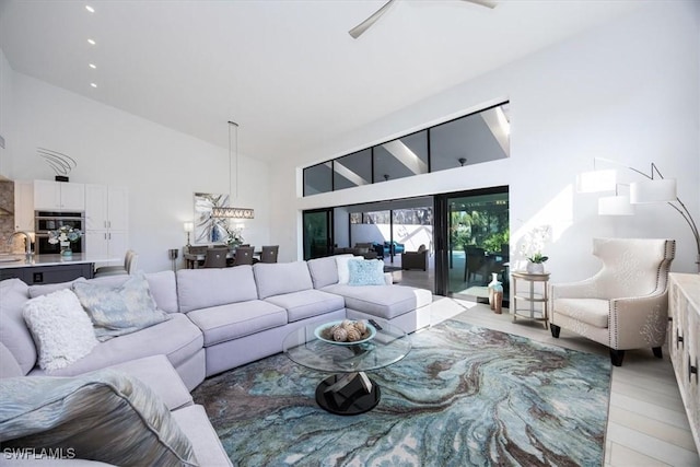 living room featuring high vaulted ceiling, ceiling fan, and light wood-type flooring