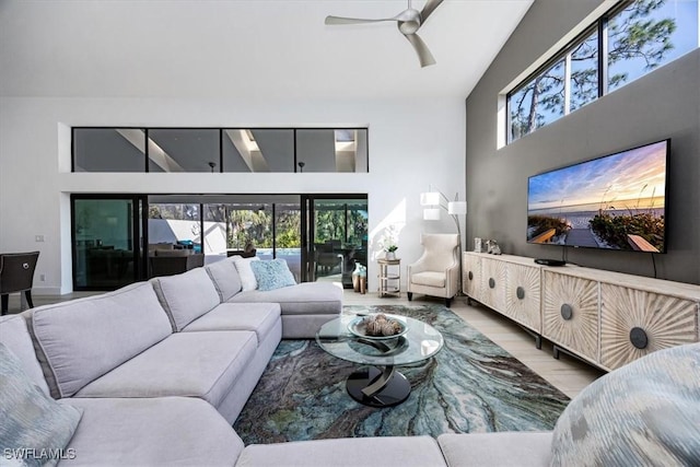 living room featuring hardwood / wood-style floors, ceiling fan, a healthy amount of sunlight, and a high ceiling