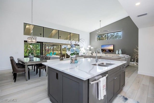 kitchen featuring sink, hanging light fixtures, light stone counters, light hardwood / wood-style flooring, and ceiling fan with notable chandelier