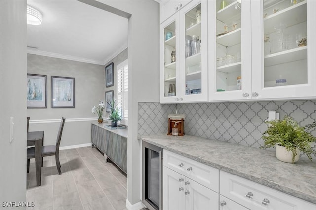 kitchen with white cabinets, wine cooler, ornamental molding, tasteful backsplash, and light stone counters