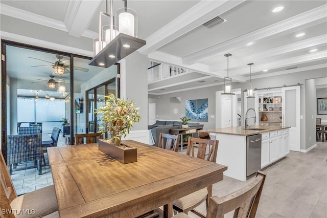 dining area with ornamental molding, ceiling fan, sink, beam ceiling, and a barn door