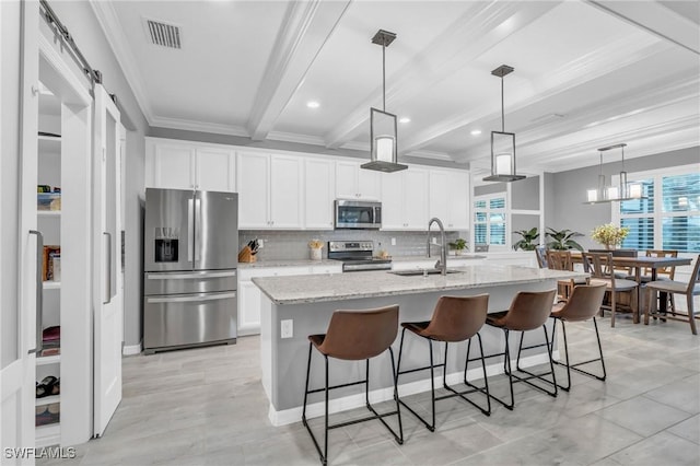 kitchen with beam ceiling, sink, stainless steel appliances, a barn door, and white cabinets