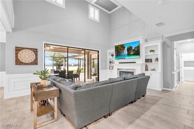 living room featuring a high end fireplace, built in shelves, and a towering ceiling