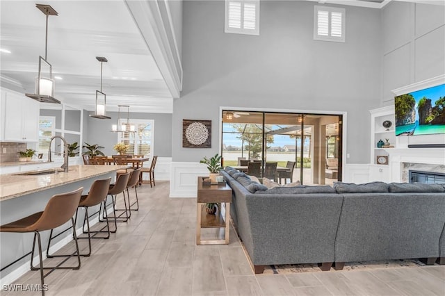 living room with ornamental molding, built in shelves, sink, a premium fireplace, and light hardwood / wood-style floors