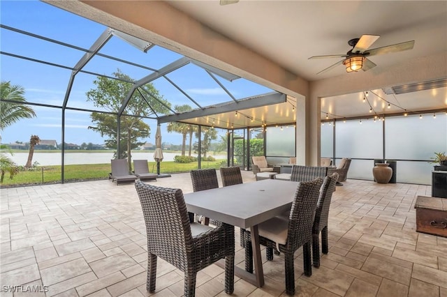 view of patio with ceiling fan, a water view, and glass enclosure