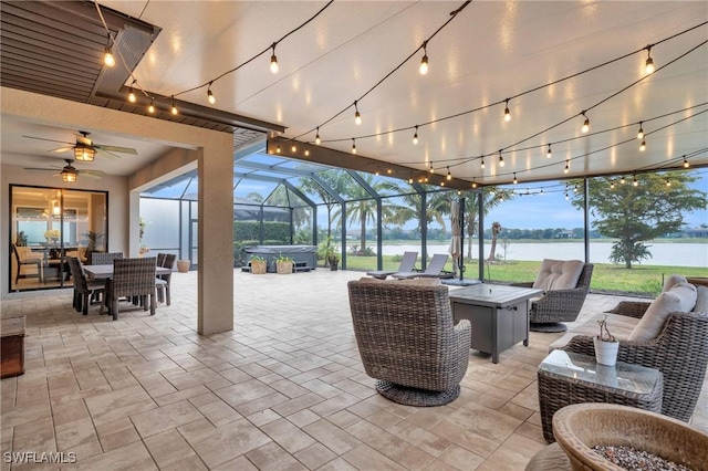 patio terrace at dusk featuring outdoor lounge area, a water view, a hot tub, and a lanai