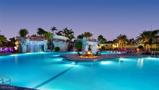 pool at dusk featuring pool water feature