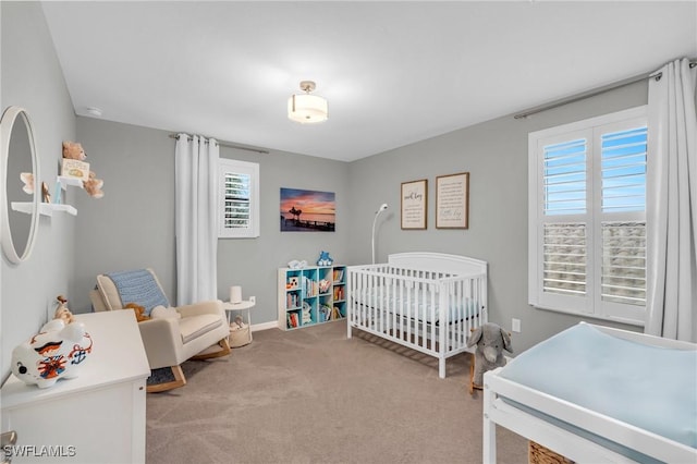 bedroom with light colored carpet and a nursery area