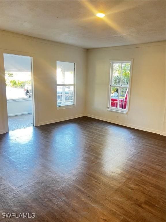 unfurnished room featuring a wealth of natural light and dark wood-type flooring