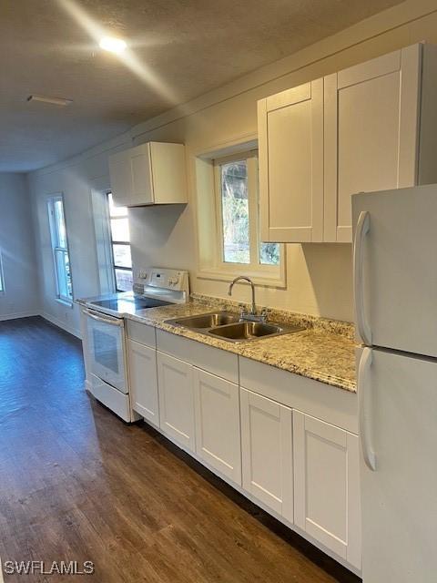 kitchen featuring white appliances, white cabinets, sink, dark hardwood / wood-style floors, and light stone countertops