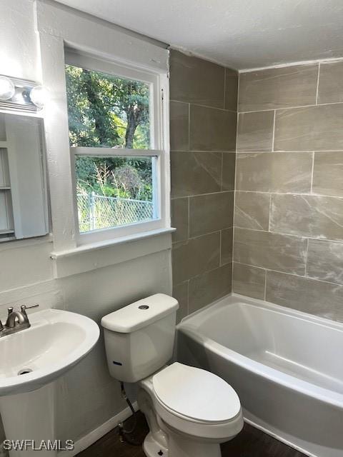 full bathroom featuring sink, toilet, and tiled shower / bath