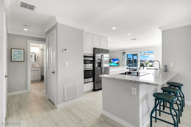 kitchen featuring white cabinets, a kitchen breakfast bar, sink, appliances with stainless steel finishes, and kitchen peninsula