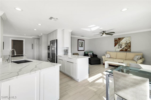 kitchen featuring light stone countertops, appliances with stainless steel finishes, ceiling fan, sink, and white cabinetry