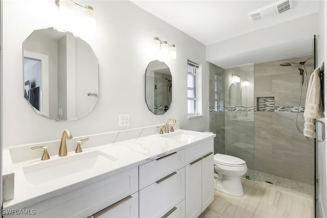 bathroom with a tile shower, vanity, and toilet