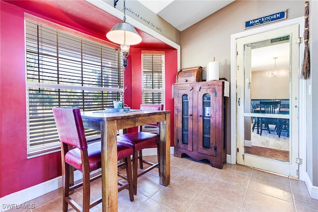 tiled dining room with vaulted ceiling and a notable chandelier