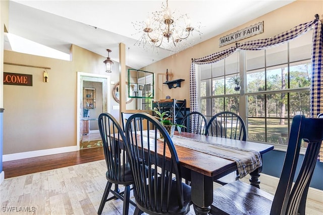 dining area featuring wood-type flooring, vaulted ceiling, and a notable chandelier