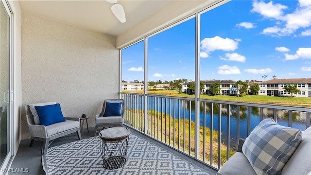 sunroom / solarium featuring a water view and ceiling fan