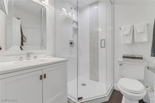 full bathroom featuring a stall shower, toilet, and vanity