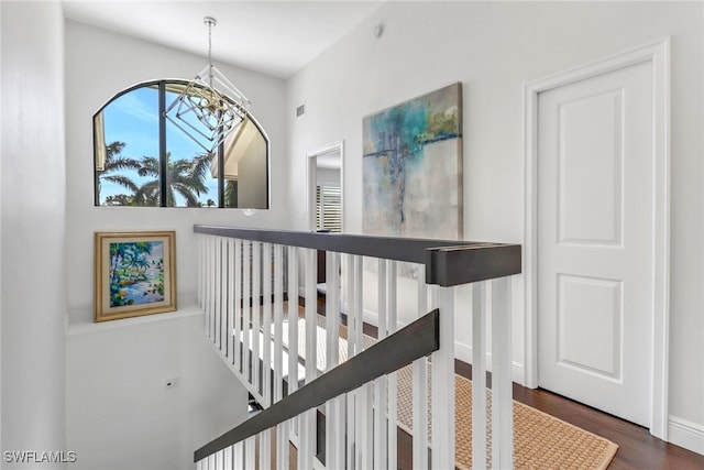 stairway with visible vents, a notable chandelier, wood finished floors, and baseboards