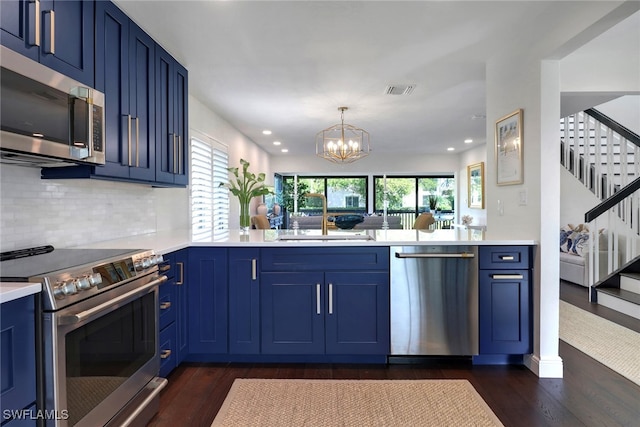 kitchen with blue cabinetry, stainless steel appliances, light countertops, and a sink