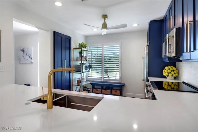 kitchen featuring stainless steel microwave, blue cabinetry, light countertops, and a sink