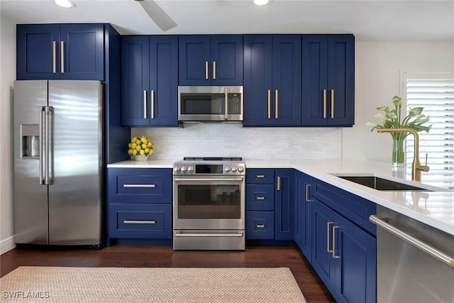 kitchen with blue cabinets, appliances with stainless steel finishes, light countertops, and a sink