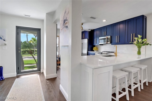 kitchen with visible vents, a sink, light countertops, stainless steel microwave, and blue cabinets