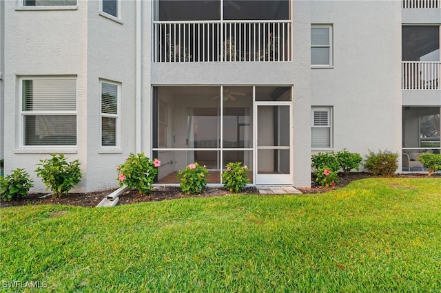 rear view of property featuring a yard and stucco siding