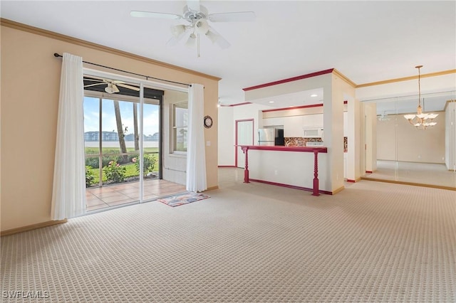 unfurnished living room featuring ceiling fan with notable chandelier, ornamental molding, baseboards, and light colored carpet