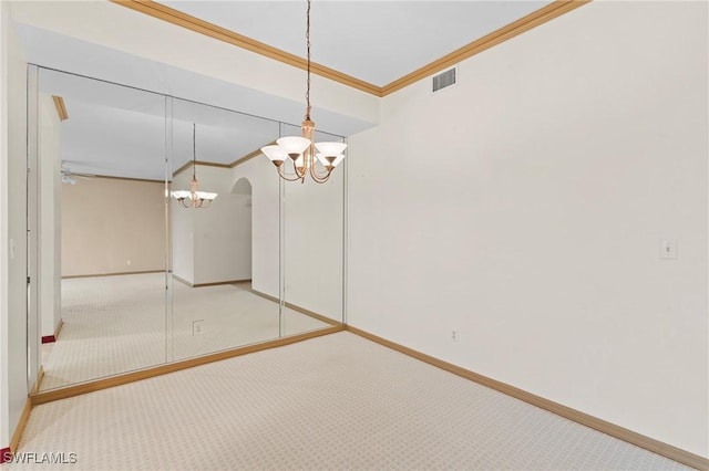 unfurnished room featuring arched walkways, light colored carpet, visible vents, baseboards, and crown molding