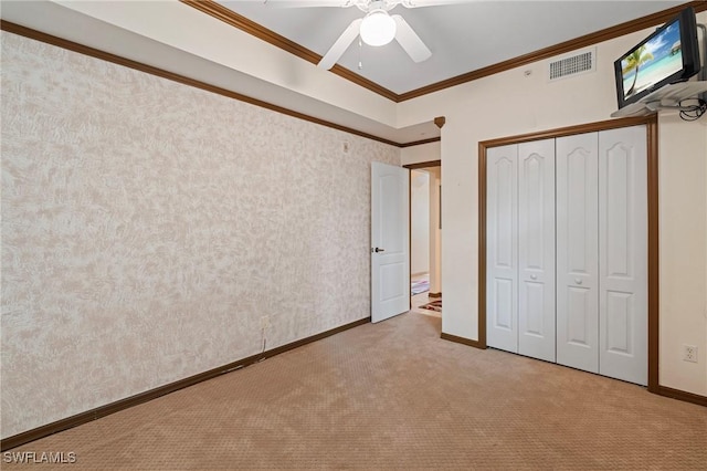 unfurnished bedroom with light carpet, visible vents, baseboards, a closet, and crown molding