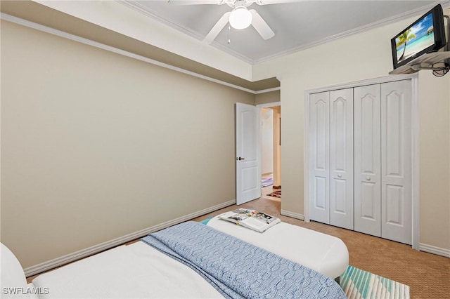 carpeted bedroom with a closet, crown molding, baseboards, and ceiling fan