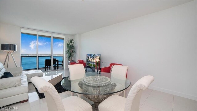 dining room featuring a water view, light tile patterned flooring, and a wall of windows