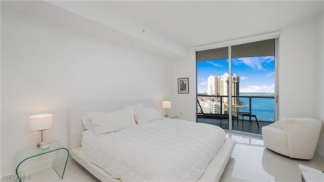 bedroom featuring floor to ceiling windows, a water view, light tile patterned flooring, and access to outside