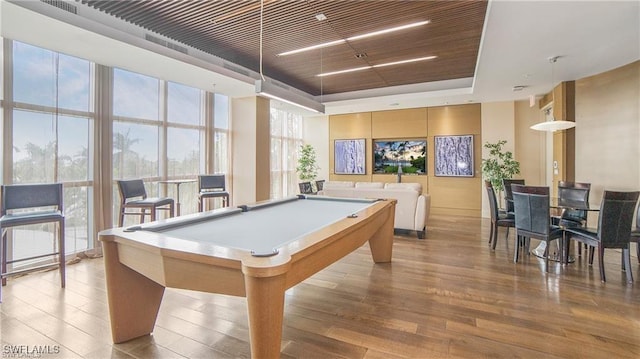 playroom featuring light hardwood / wood-style flooring, a raised ceiling, a wall of windows, and billiards