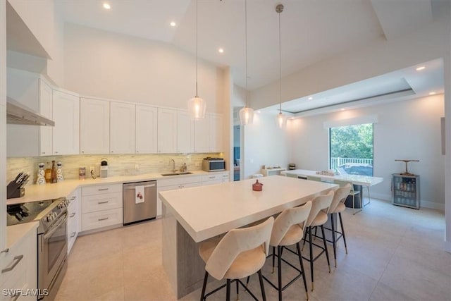 kitchen featuring a center island, a kitchen breakfast bar, pendant lighting, white cabinets, and appliances with stainless steel finishes