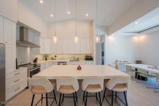 kitchen featuring a center island, white cabinetry, wall chimney range hood, and appliances with stainless steel finishes