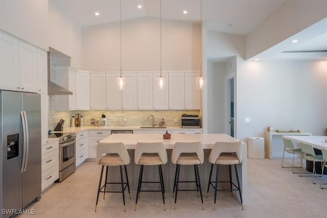 kitchen with white cabinets, high vaulted ceiling, hanging light fixtures, and appliances with stainless steel finishes