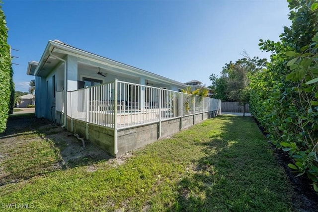 view of home's exterior featuring ceiling fan and a lawn