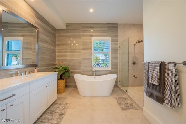 bathroom featuring vanity, independent shower and bath, and tile walls