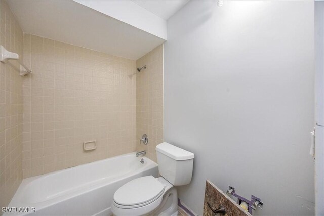 bathroom featuring tiled shower / bath and toilet