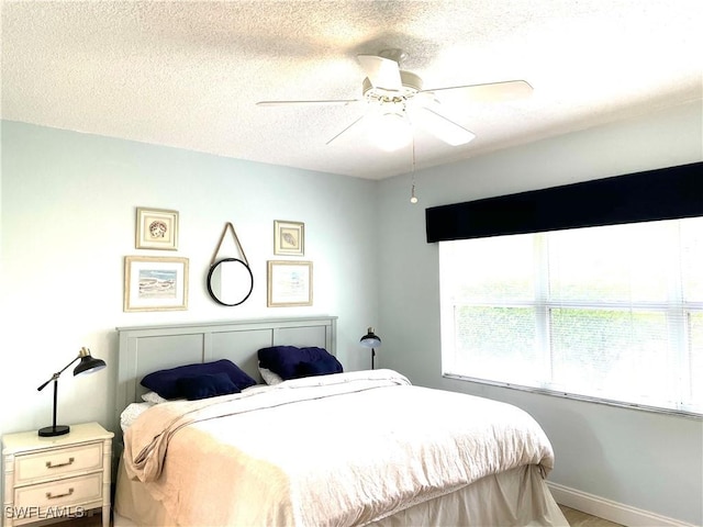 bedroom with ceiling fan and a textured ceiling