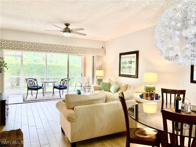 living room featuring ceiling fan, light hardwood / wood-style floors, and a textured ceiling