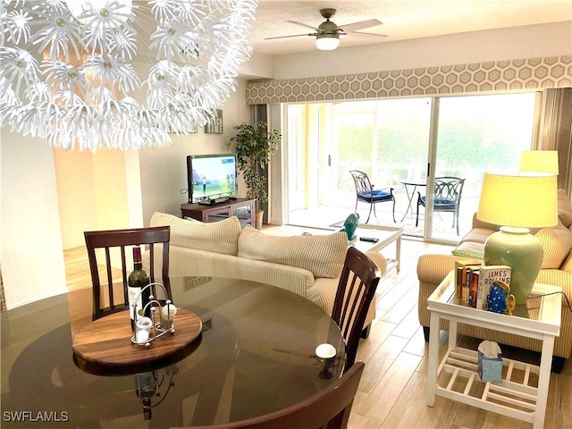 living room featuring ceiling fan with notable chandelier and light hardwood / wood-style flooring